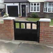 Red brick garden wall with capped piers and timber gate